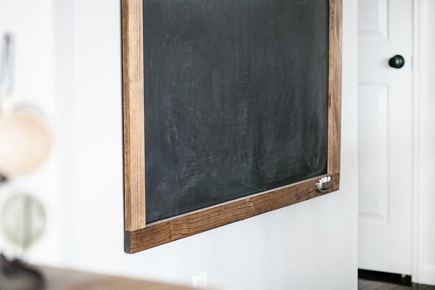 Oversized black chalkboard with a rustic wood frame hanging on a white wall