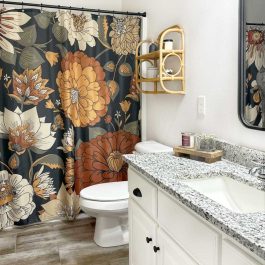 Clean bathroom with a white vanity, granite countertop, floral shower curtain, toilet, and wood-look tile flooring.