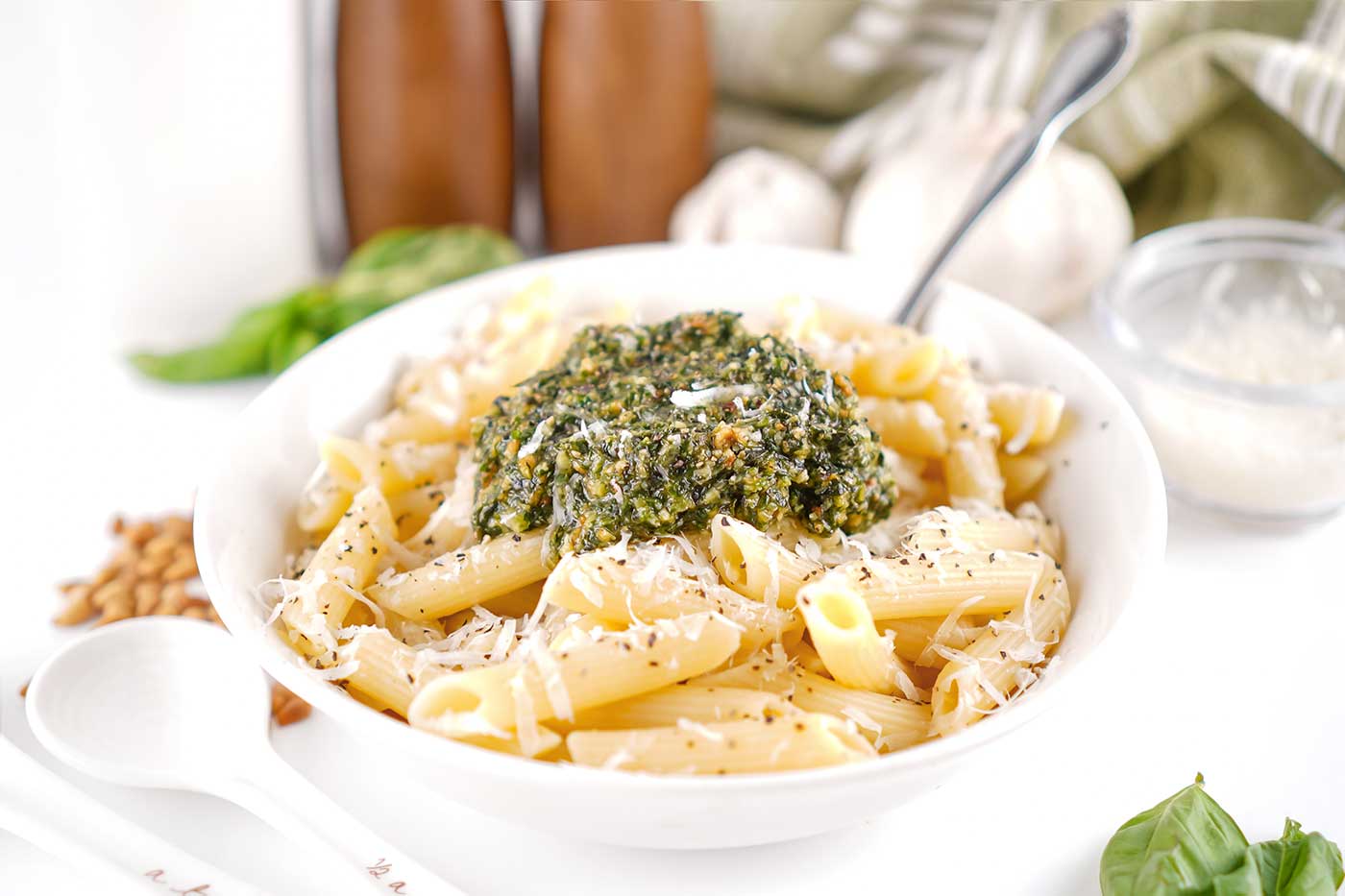 Bowl of pasta topped with homemade basil pesto and grated Parmesan cheese.