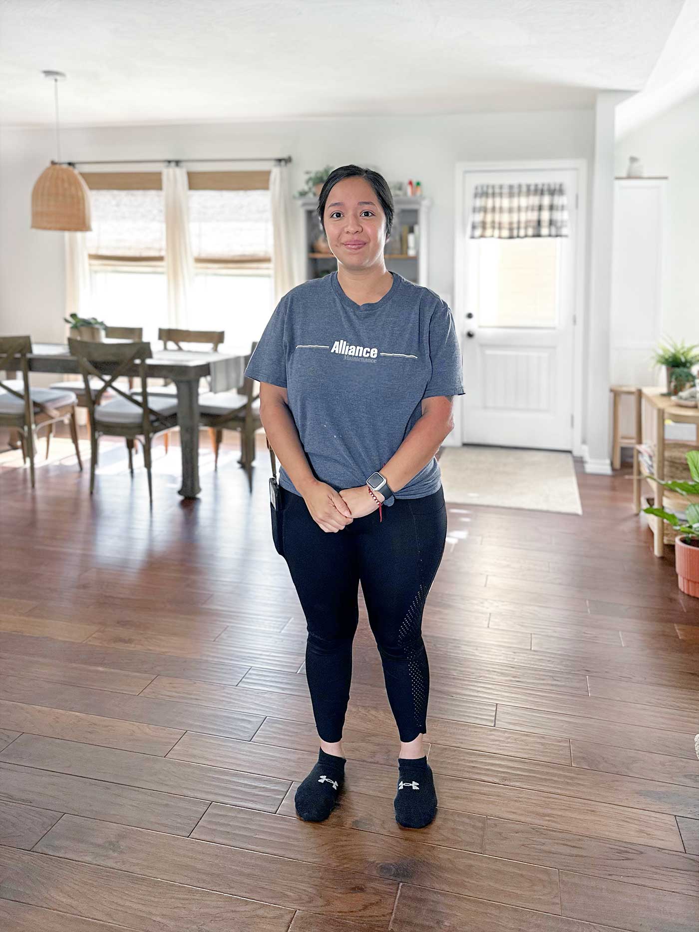Homeaglow cleaner standing in a bright dining and living area after completing a home cleaning appointment.