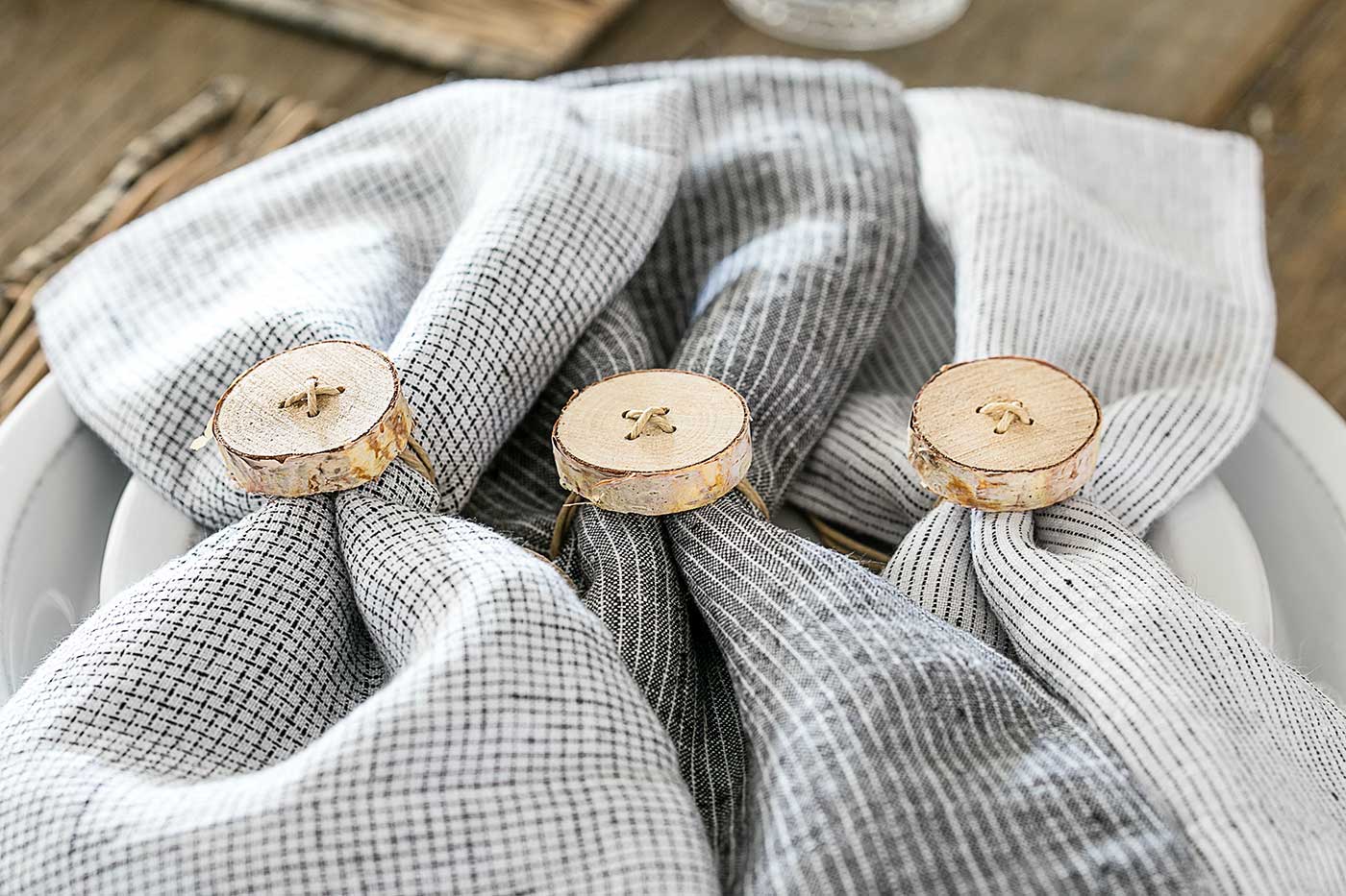 Rustic birch wood napkin rings wrapped around neutral cloth napkins
