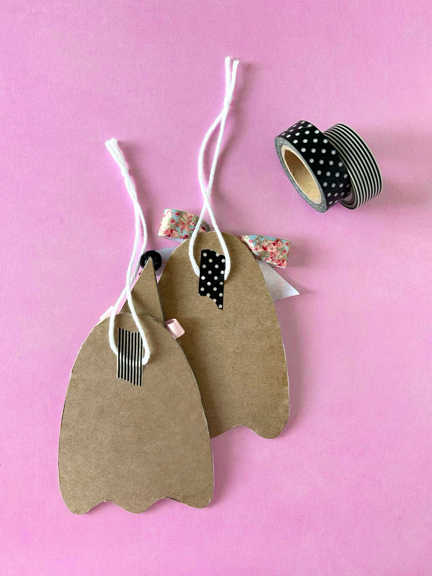 Back of handmade felt ghost ornaments showing string hangers attached with decorative tape