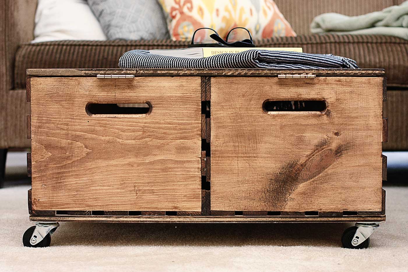Rustic wooden storage ottoman with two crate-style compartments and caster wheels