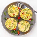 Four egg bites with cottage cheese, spinach, and red bell pepper served on a gray plate