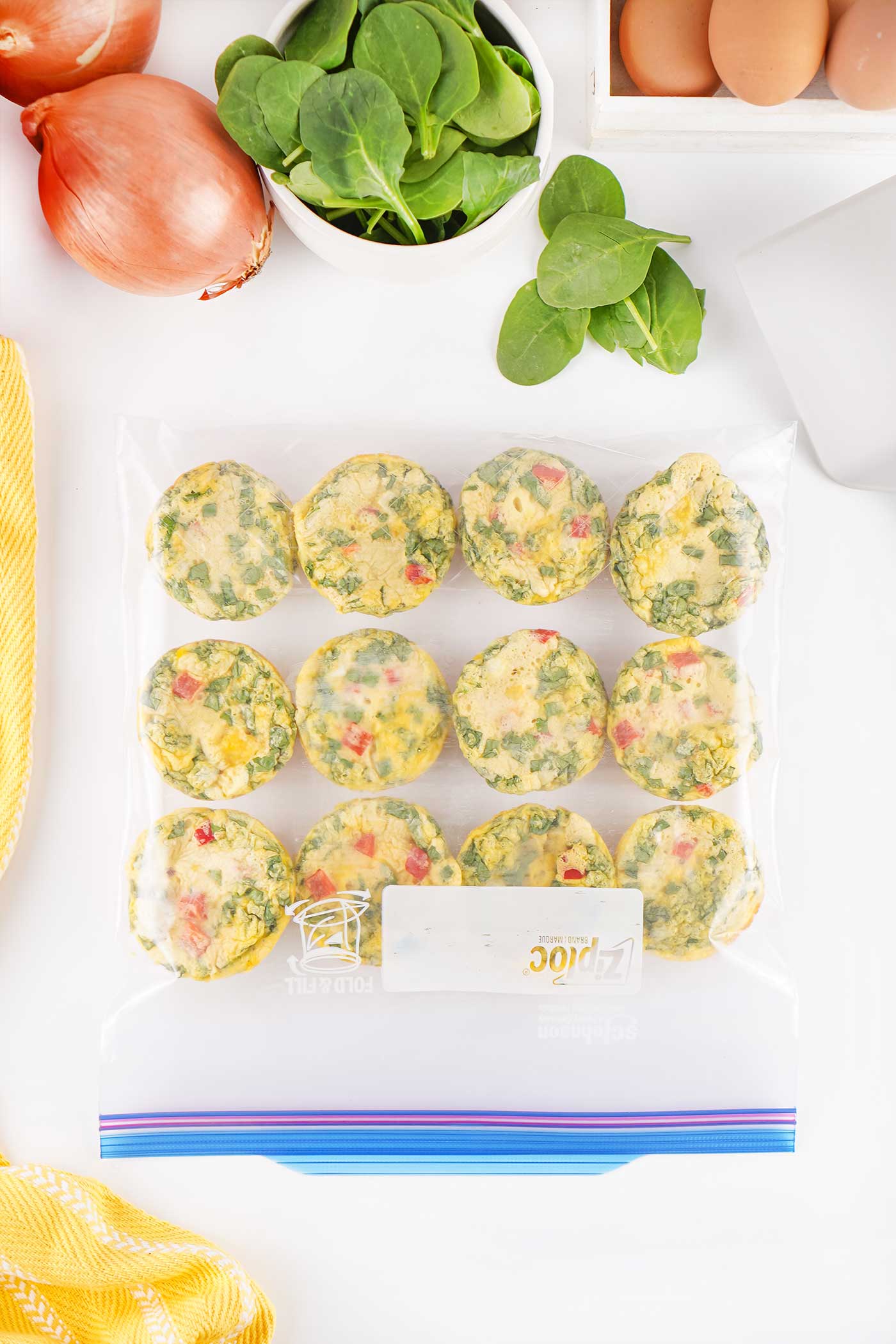 Homemade egg bites with spinach and red bell pepper stored in a freezer bag