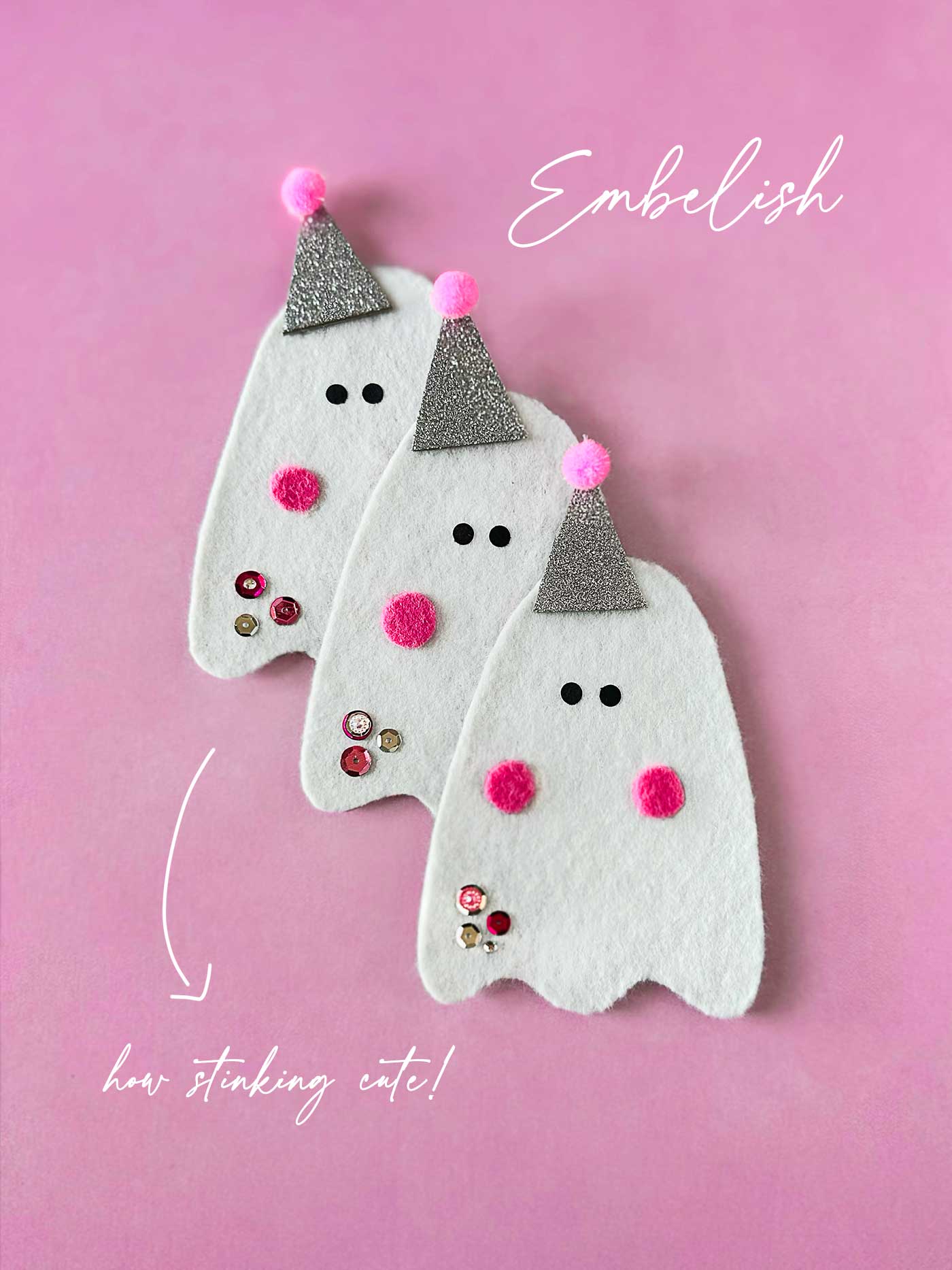 Three handmade felt ghosts with glitter party hats and pink felt cheeks on a pink background