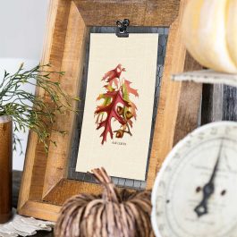 Vintage oak leaves and acorns fall printable clipped inside a rustic wood frame with a decorative pumpkin and antique kitchen scale
