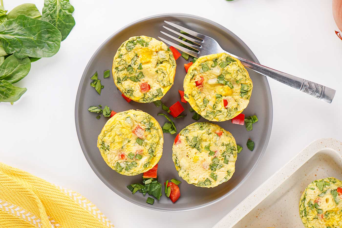 Four vegetable egg bites with cottage cheese served on a gray plate with a fork