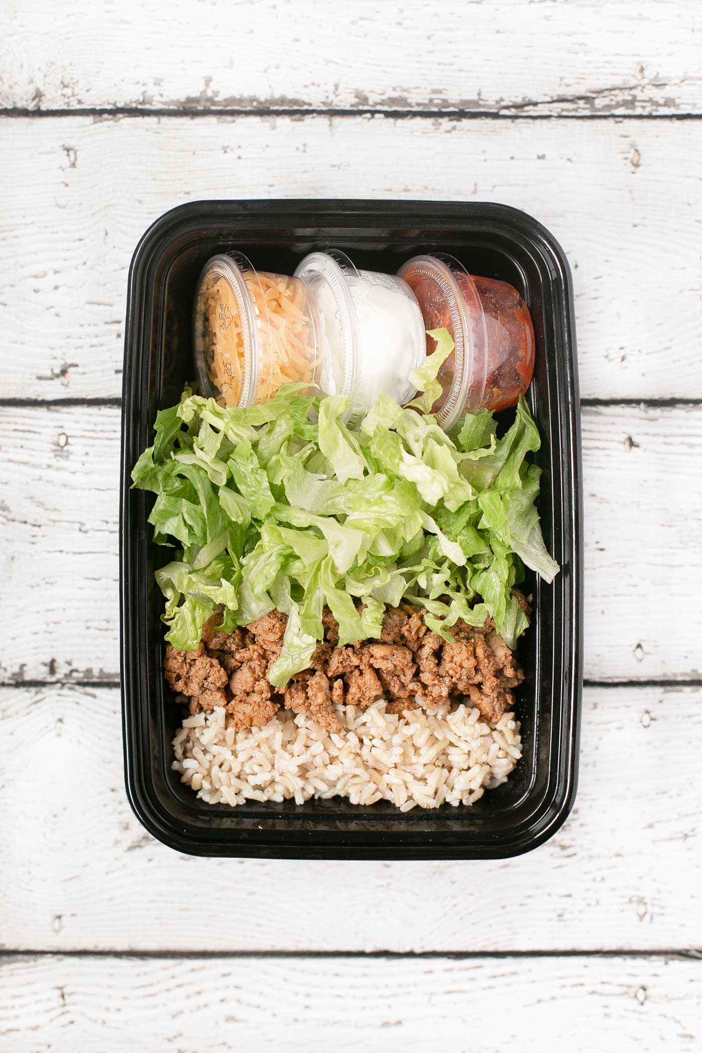 Grab-and-God Easy taco salad with seasoned meat, romaine lettuce, rice, and toppings in a divided container.